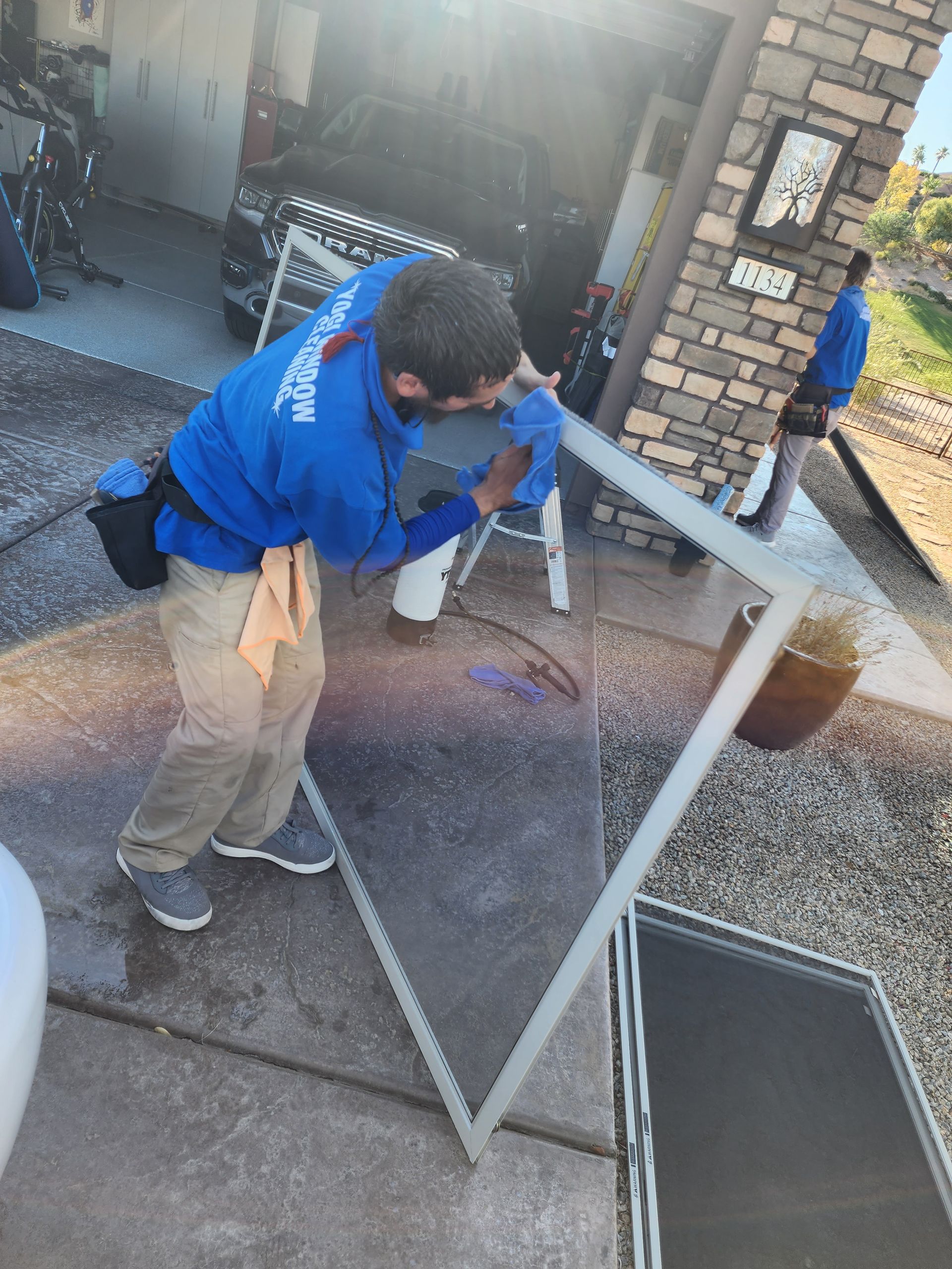 A man is cleaning a screen door outside of a house.