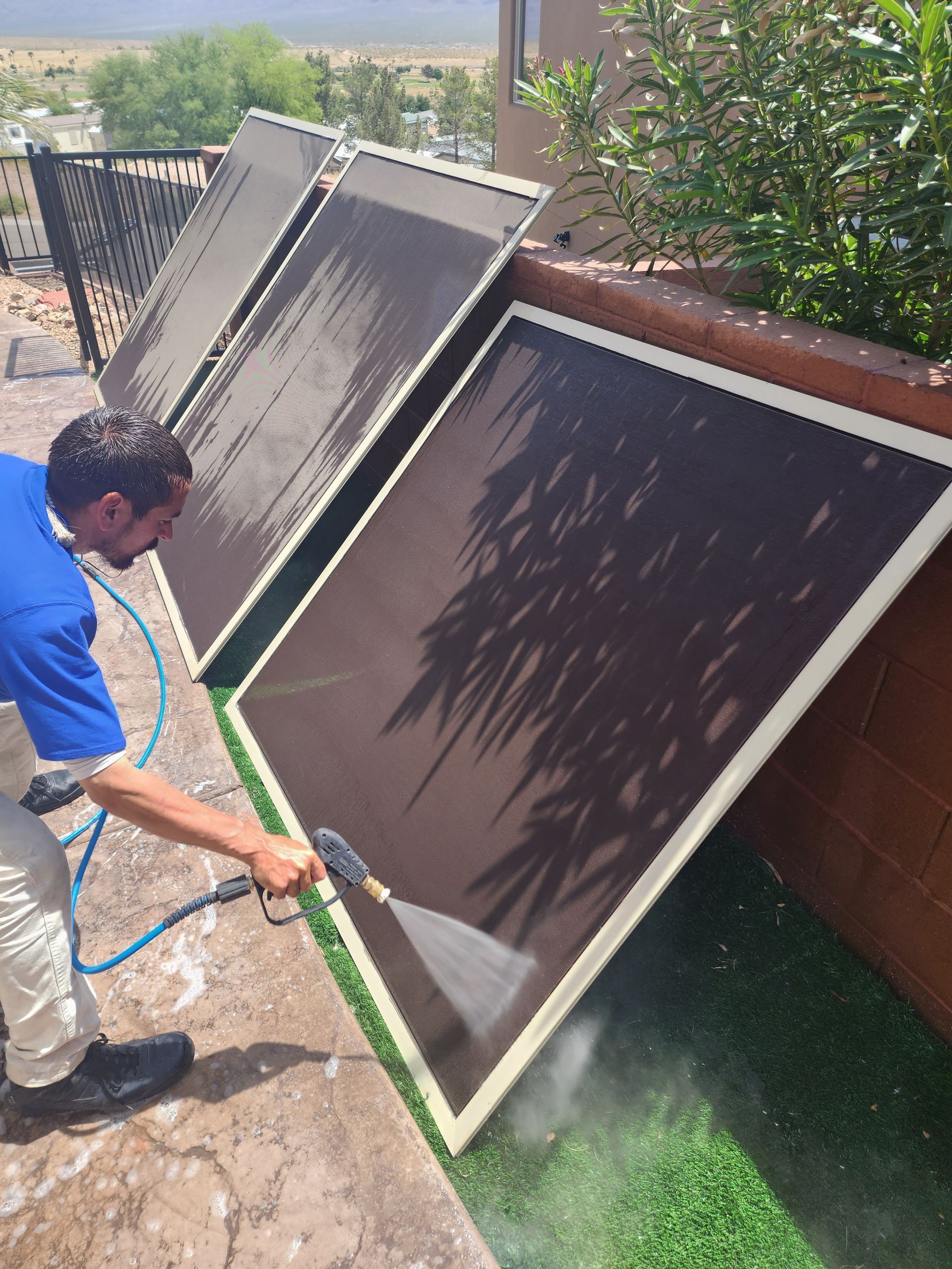 A man is cleaning a solar panel with a hose.