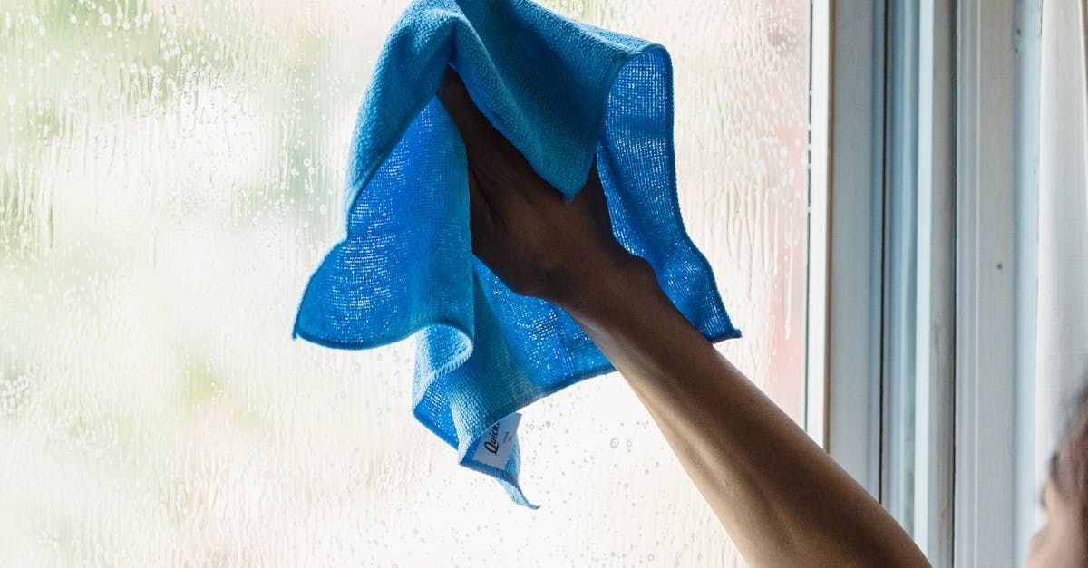 A person is cleaning a window with a blue towel.