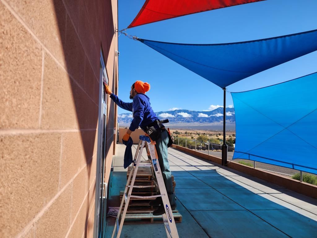 A man on a ladder is cleaning a window on the side of a building.