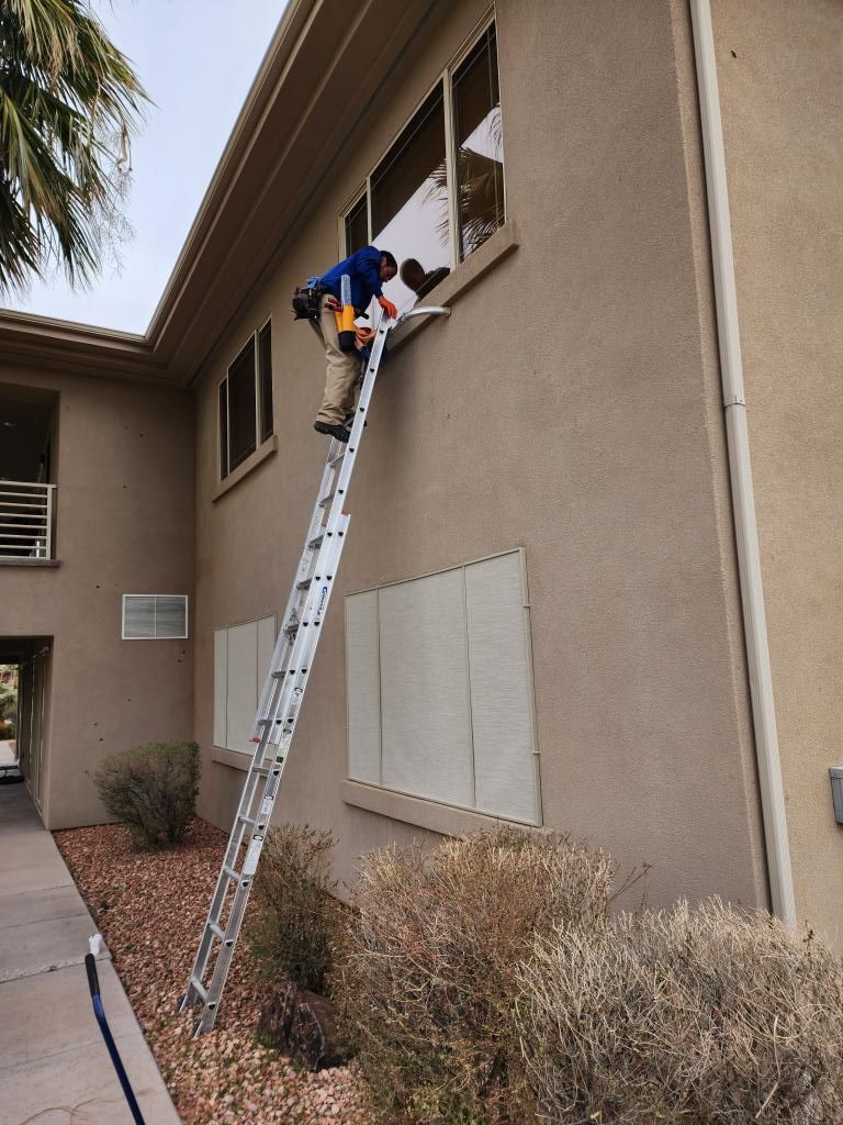 A man on a ladder is cleaning a window on the side of a building.