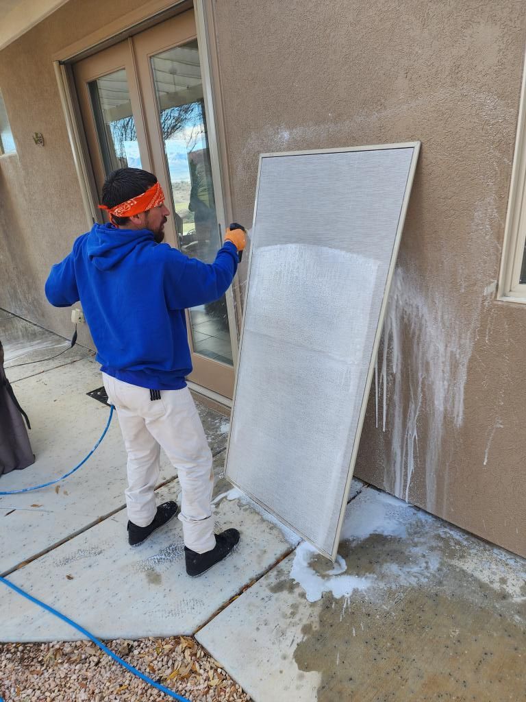 A man in a blue hoodie is cleaning a wall with a hose.