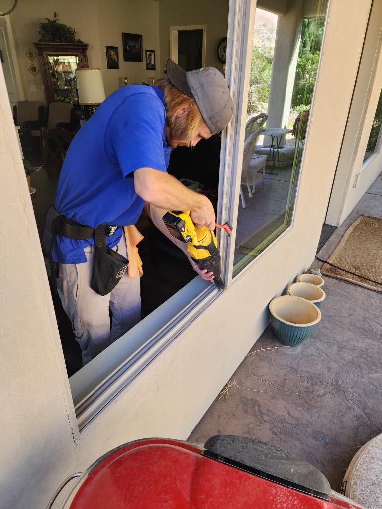 A man is working on a window with a drill in a living room.
