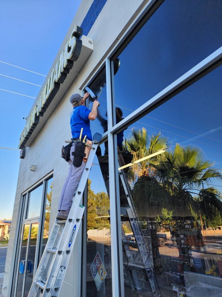 A man is standing on a ladder cleaning a window.