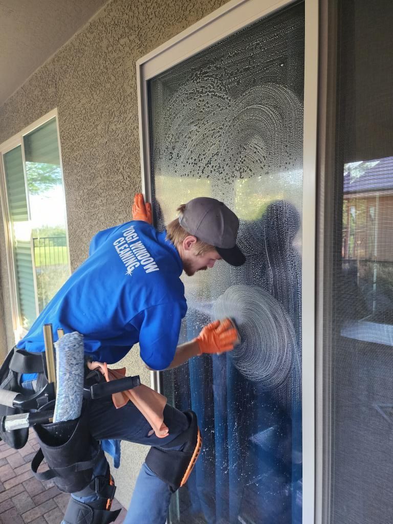 A man is cleaning a sliding glass door with a sponge.