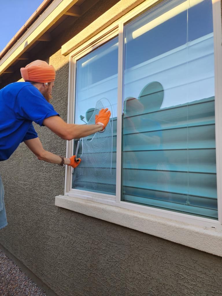 A man is cleaning a window with an orange cloth.