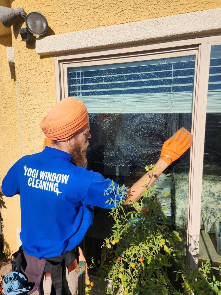 A man in a blue shirt is cleaning a window.