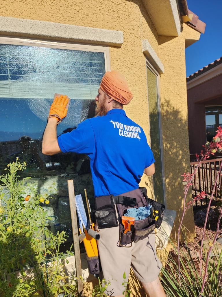 A man in a blue shirt is cleaning a window.
