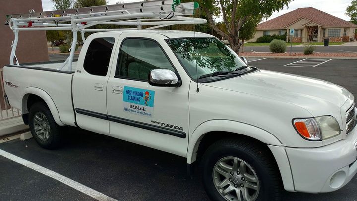 A white truck is parked in a parking lot in front of a building.