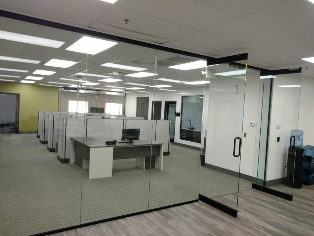 A large office with cubicles and a glass wall.