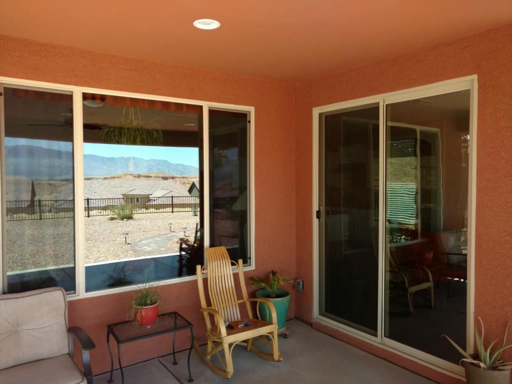 A rocking chair is sitting on a patio next to a window.
