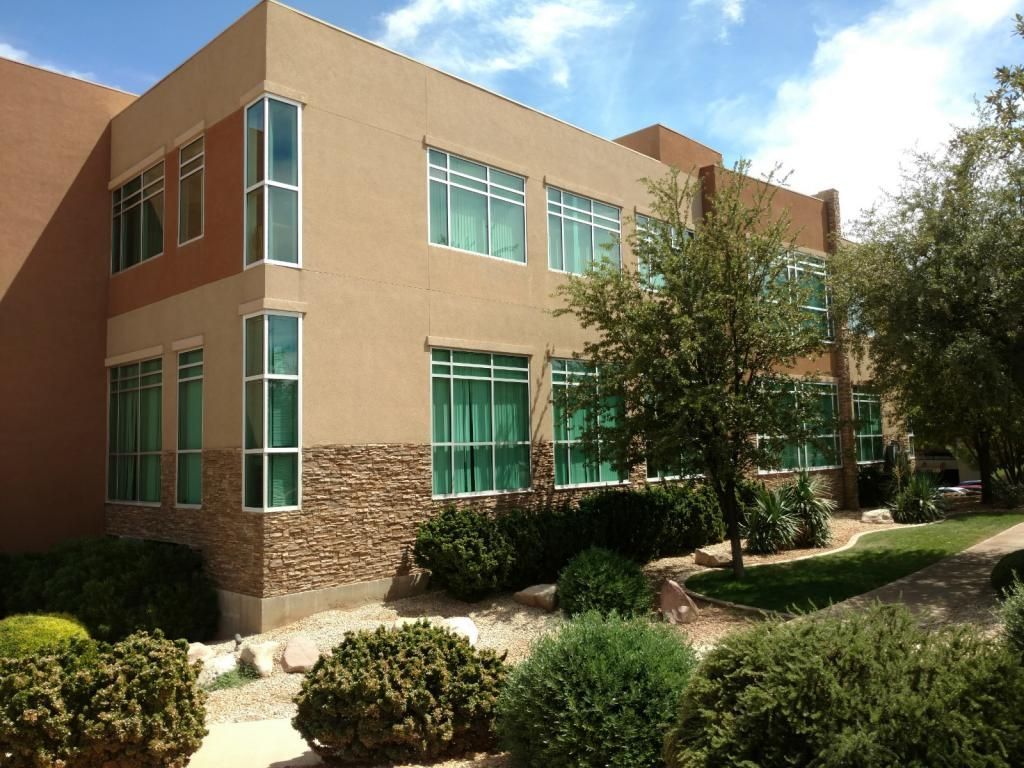 A large building with lots of windows and bushes in front of it