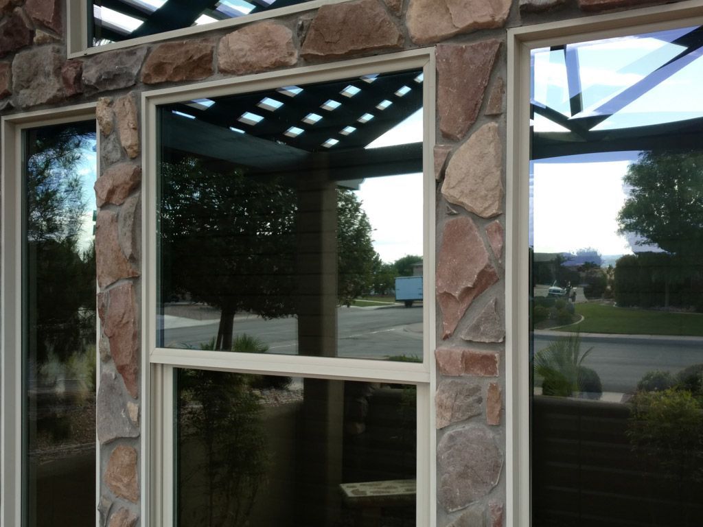 A stone building with a reflection of trees in the windows