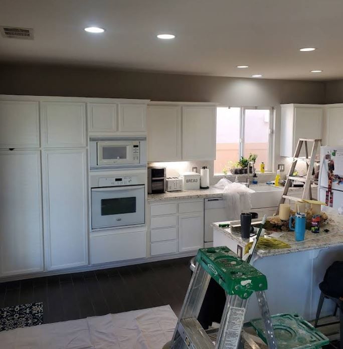 A kitchen with white cabinets and a green ladder