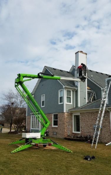 A man is working on the roof of a house with a green lift