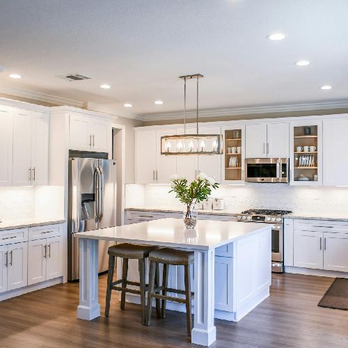 A kitchen with white cabinets , stainless steel appliances and a large island.