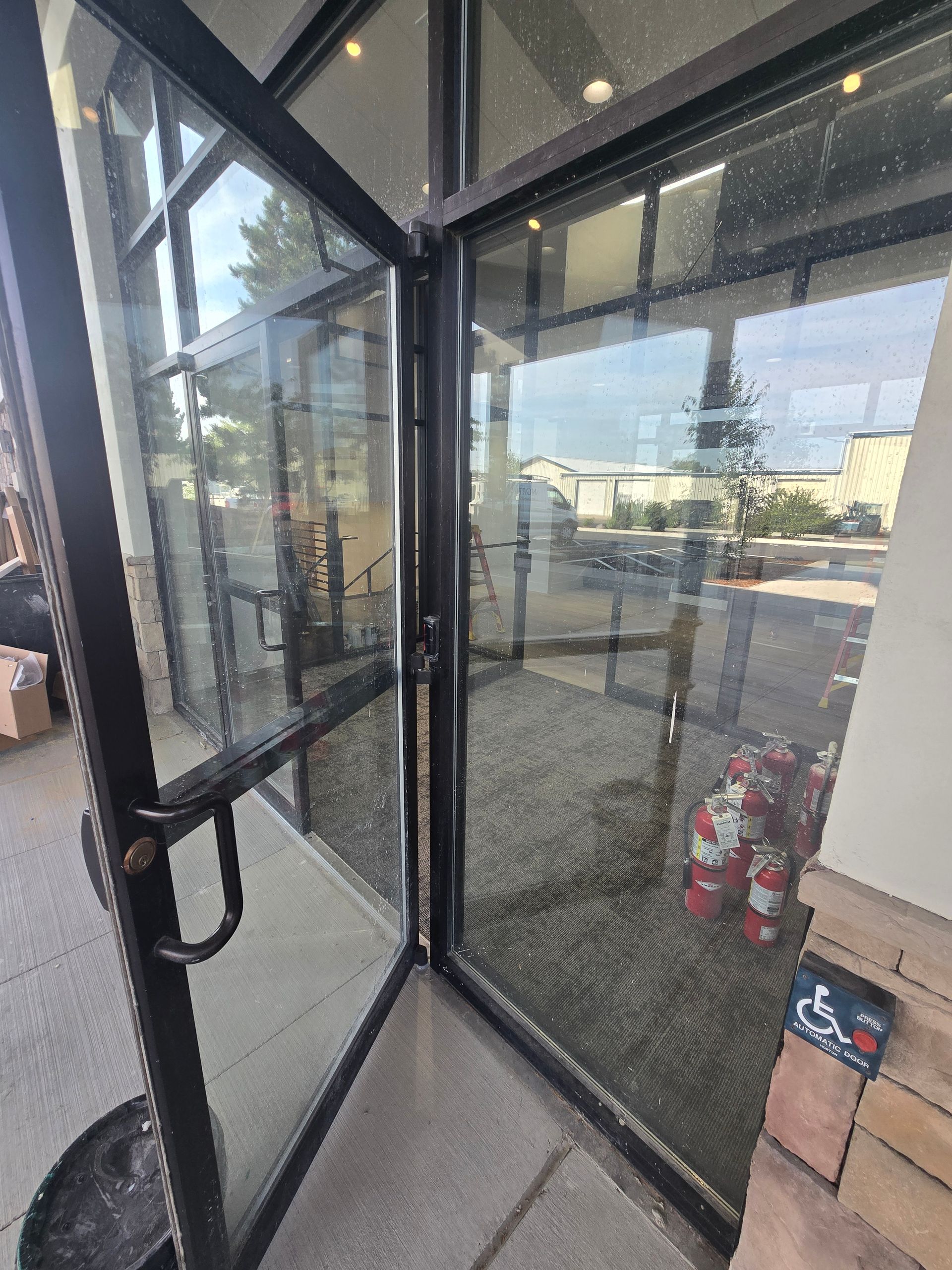 A glass door partially open to a shop entrance with a small blue wheelchair access sign visible on the wall below.
