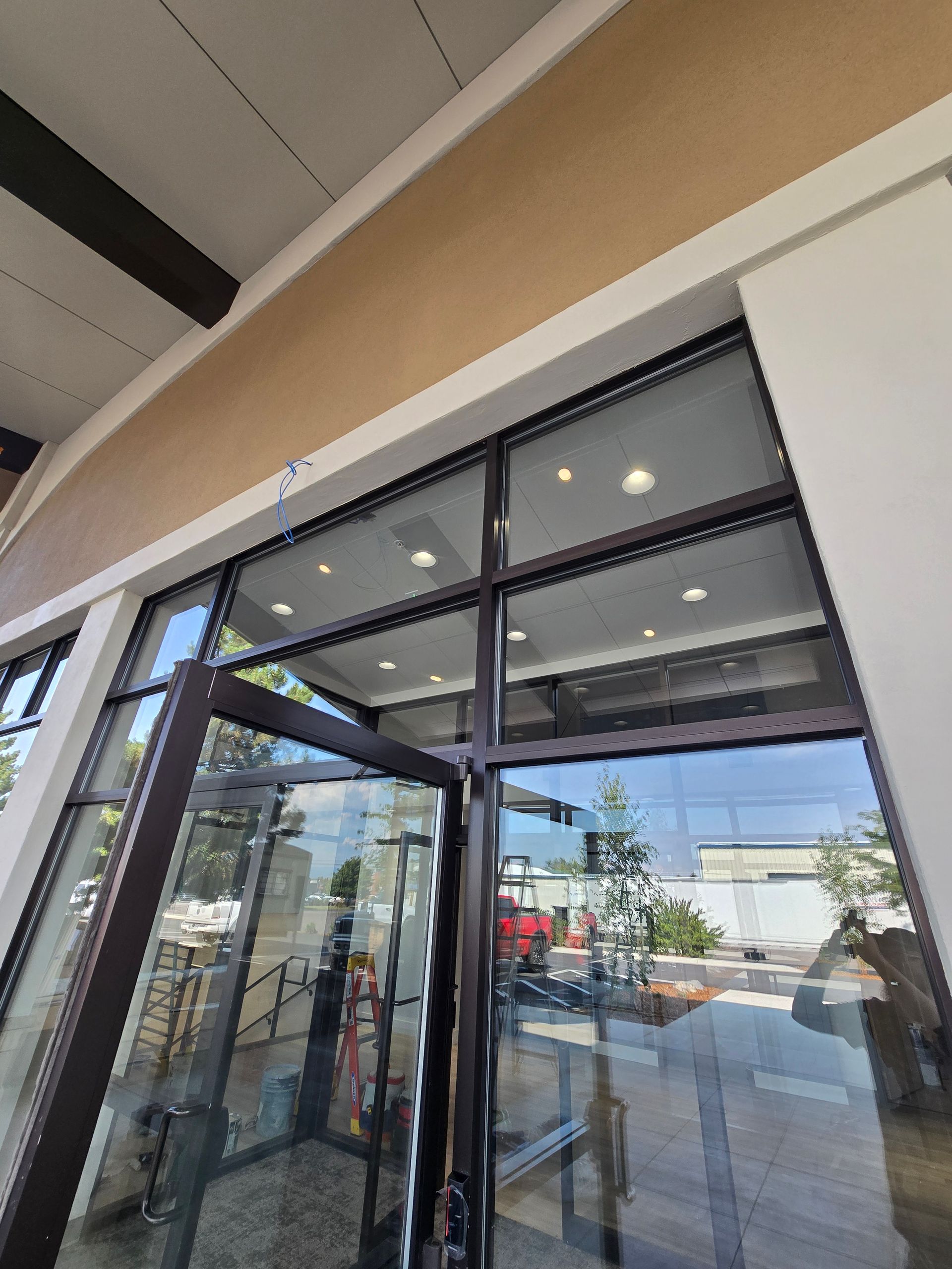 A wide-angle, low-angle shot of a glass entry door and transom windows at a building entrance with a beige exterior.