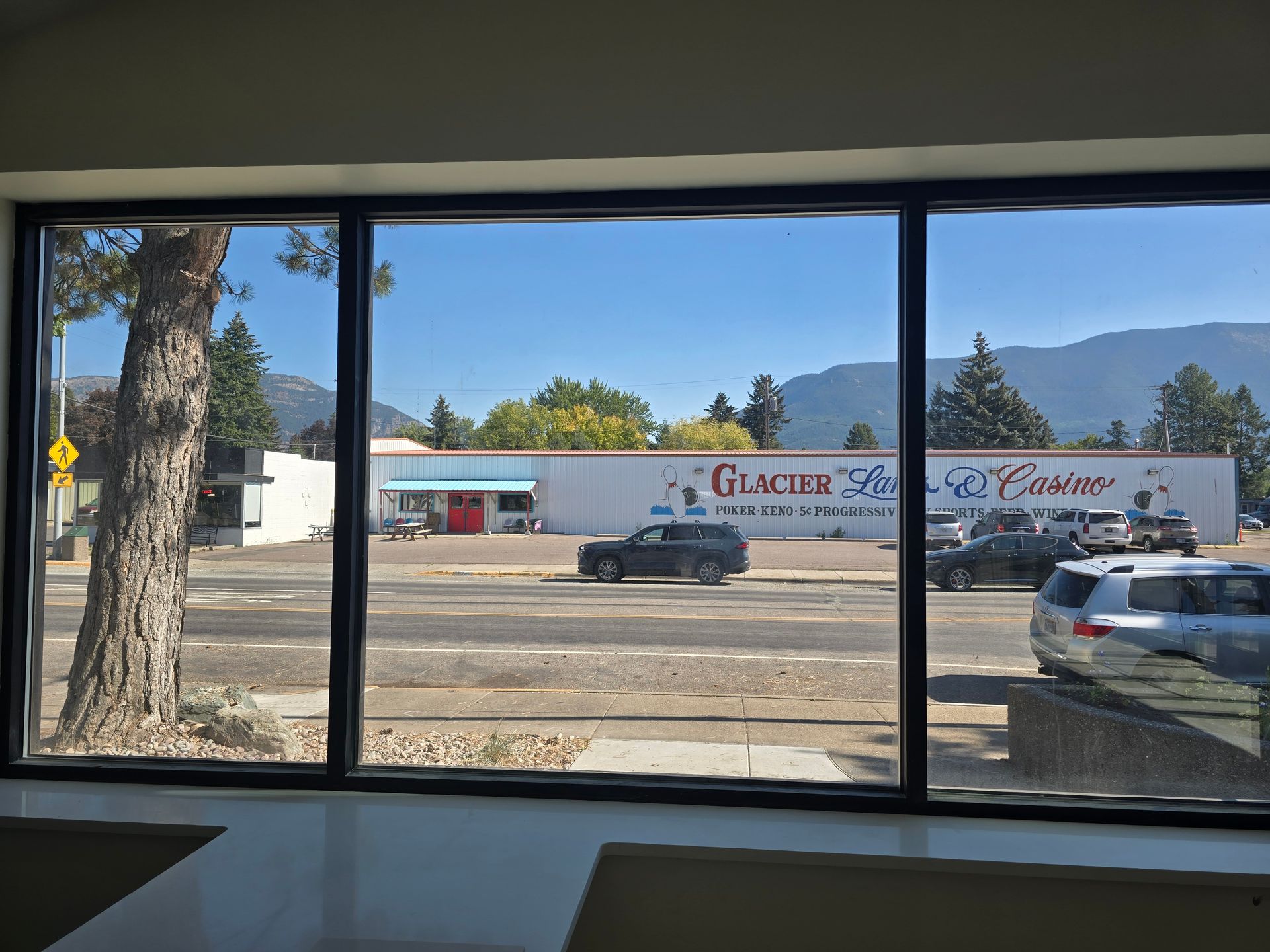 View through a window showing a street, a parking lot, and a business labeled 