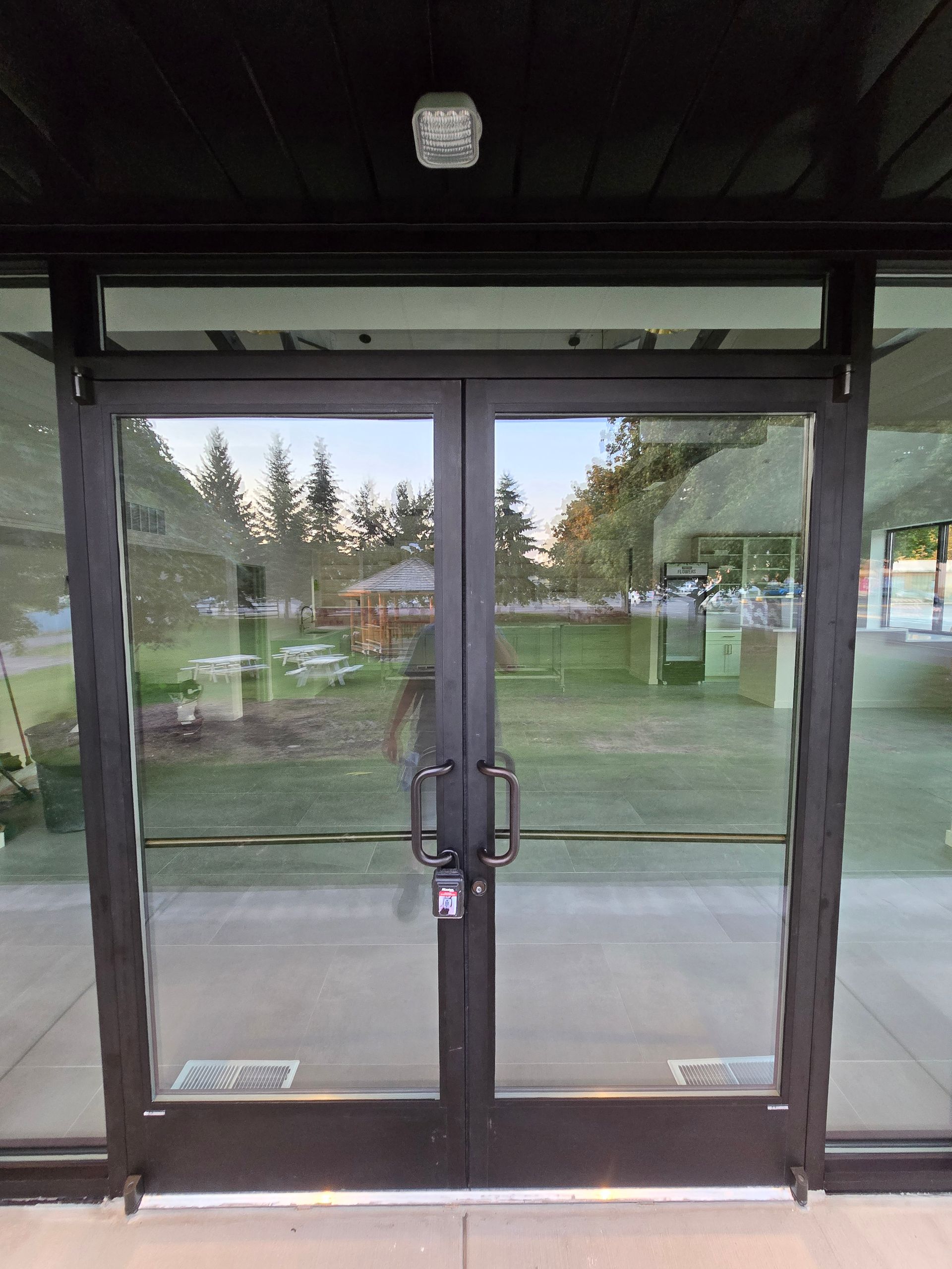 Double glass doors with dark metal frames and vertical handle bars, situated at the entrance of a building.
