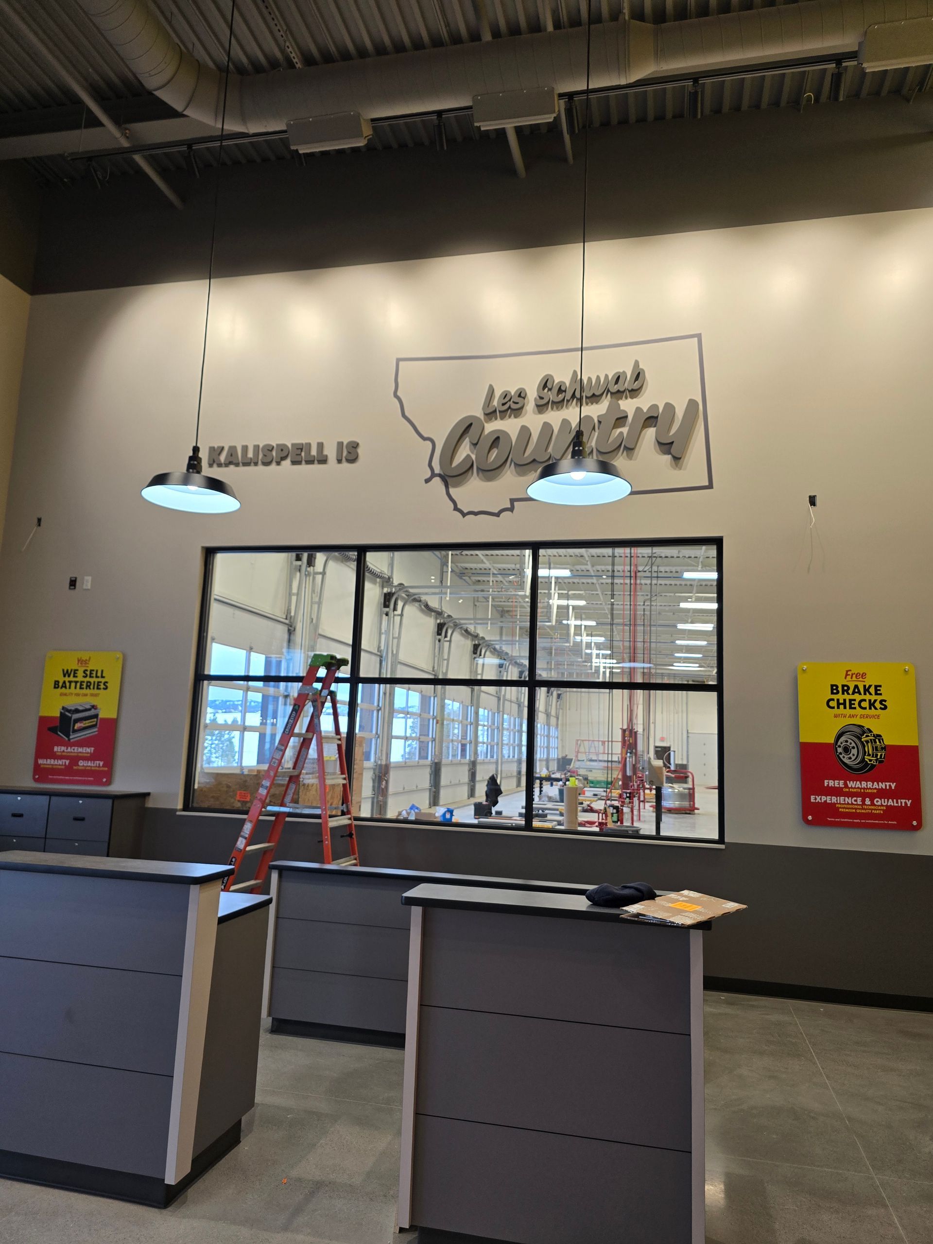 A Les Schwab Tire Center lobby with counters, a glass wall looking into the garage, and signage for 