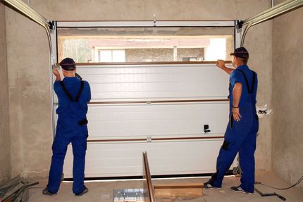 Two men are installing a garage door in a garage.