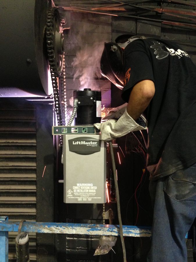 A man is working on a garage door with a drill.