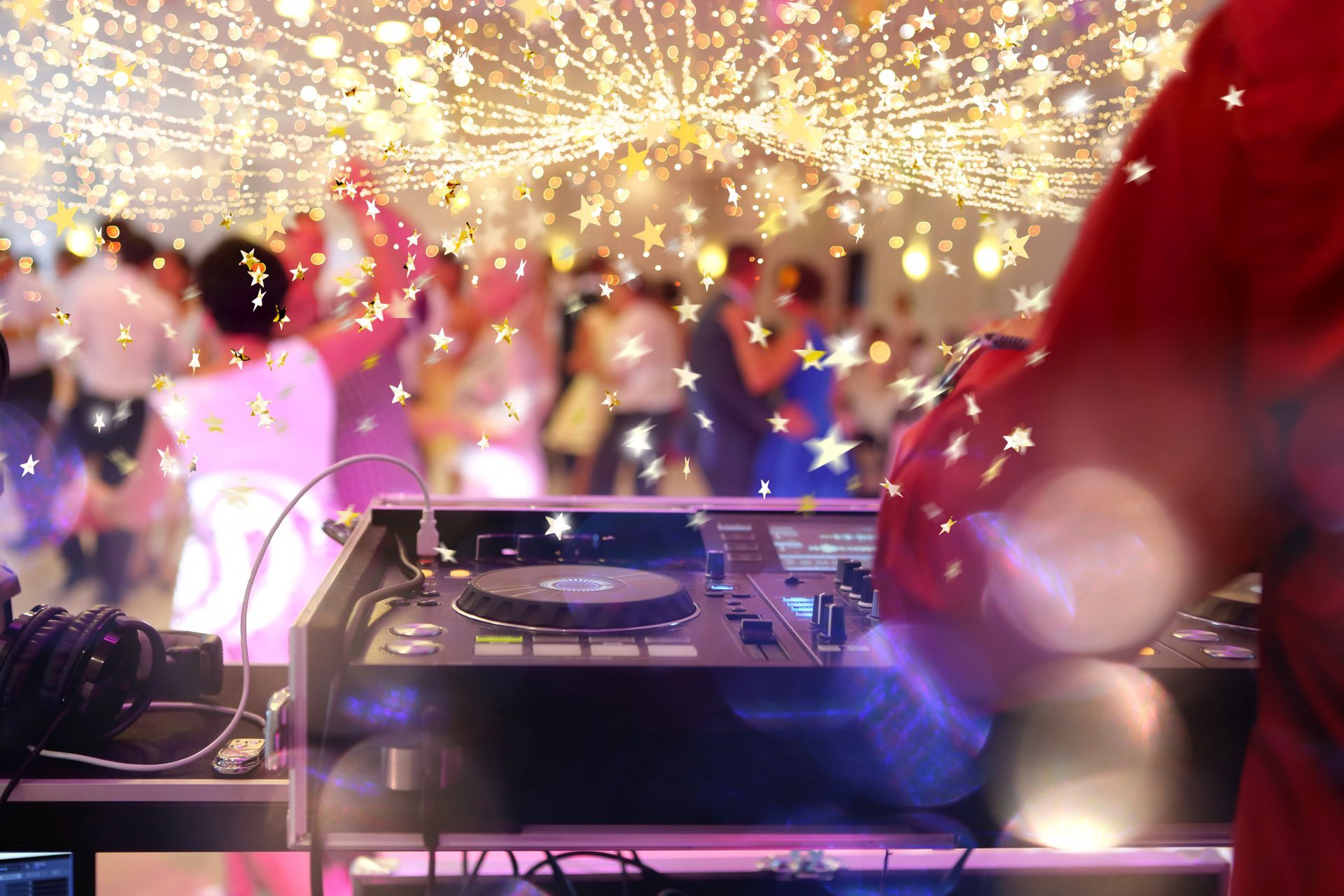 DJ at a dance party. People dancing with bright lights and a starry ceiling.