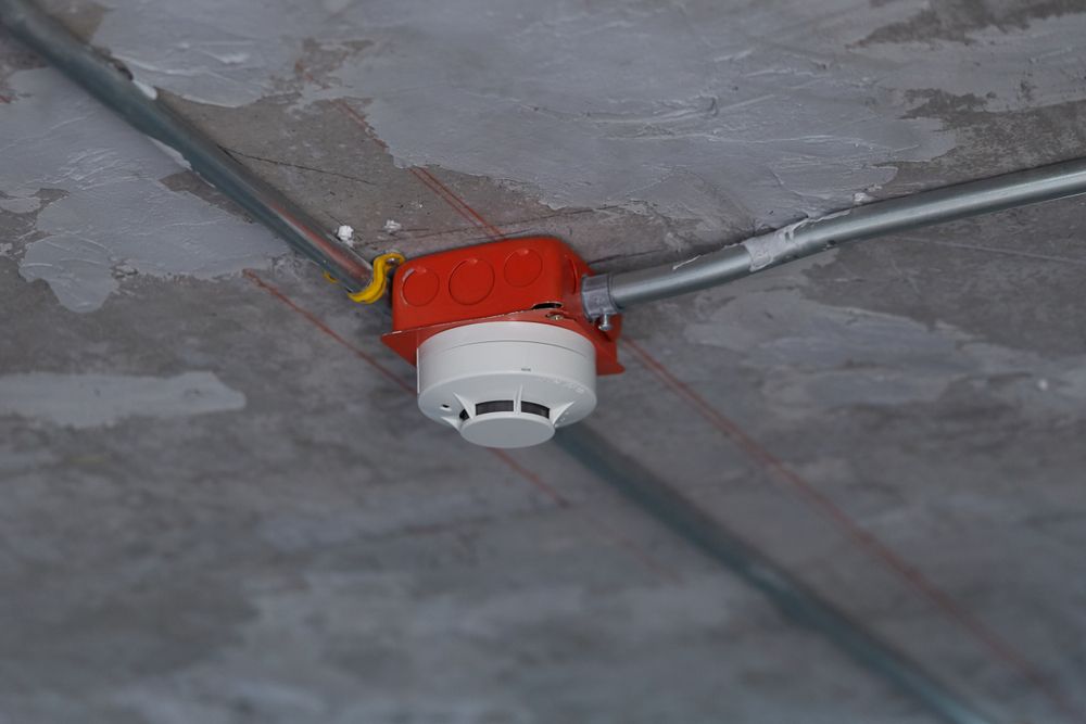 Smoke Detector and Wiring on a Gray Concrete Ceiling — Hutchy's Refrigeration & Electrical in Trinity Park, QLD