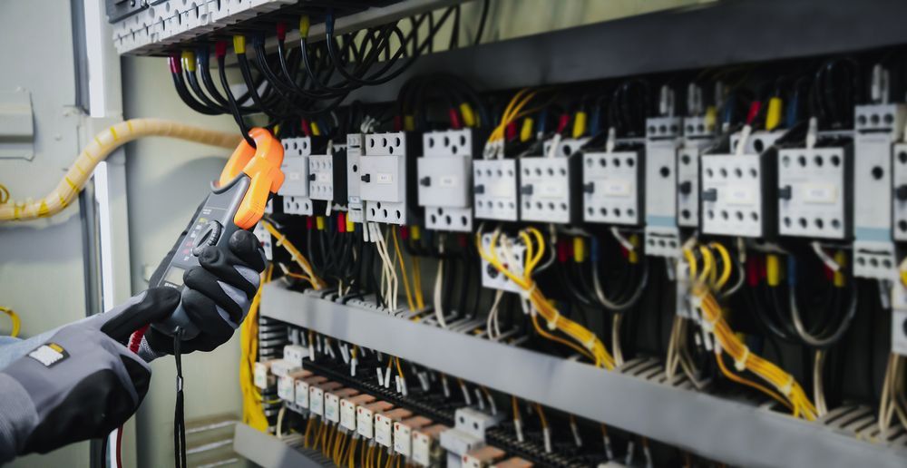 A Person is Working on an Electrical Panel With a Clamp — Hutchy's Refrigeration & Electrical in Torres Strait, QLD