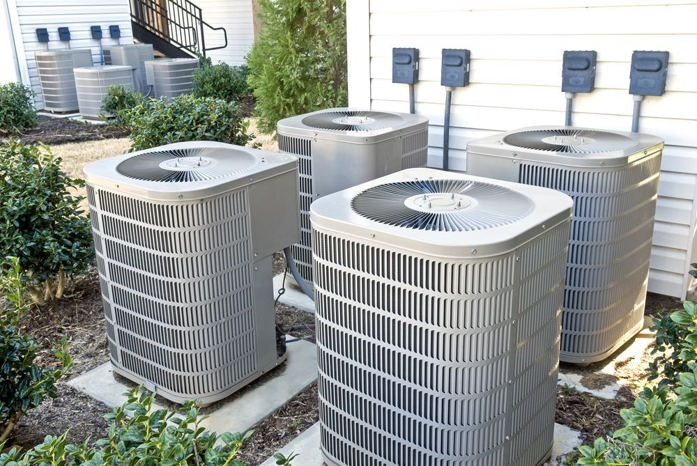A Row of Air Conditioners Are Sitting Outside of a Building — Hutchy's Refrigeration & Electrical in Townsville, QLD