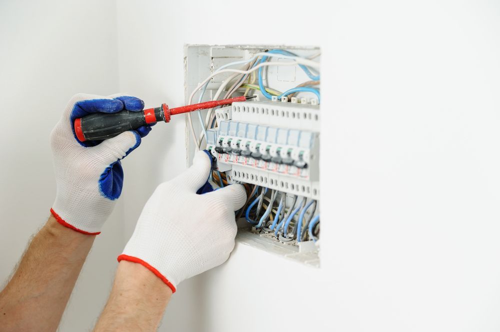 Person Wearing Gloves Using a Screwdriver on a Circuit Breaker Panel — Hutchy's Refrigeration & Electrical in Gordonvale, QLD