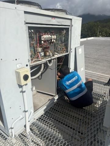 HVAC technician working on the electrical components of an air conditioning unit outdoors