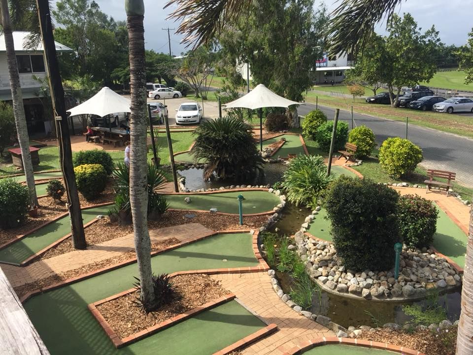 An aerial view of a mini golf course surrounded by trees and umbrellas.