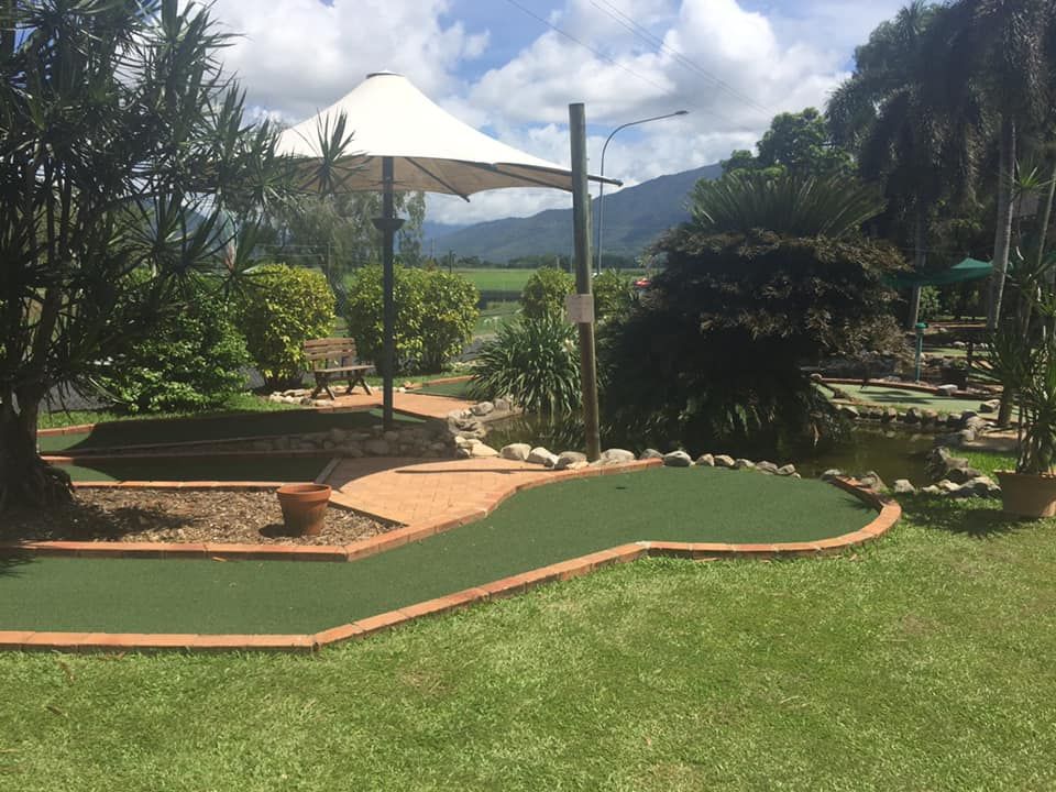 A small golf course with a white umbrella in the background.