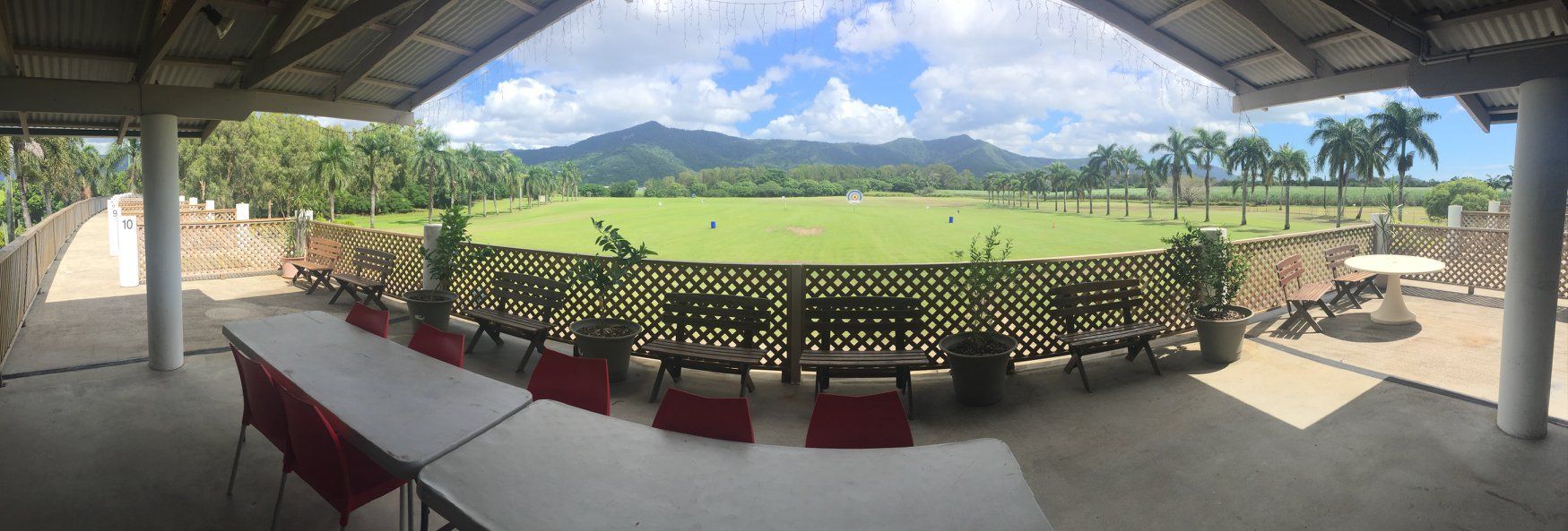 A large table and chairs are sitting under a canopy overlooking a field.