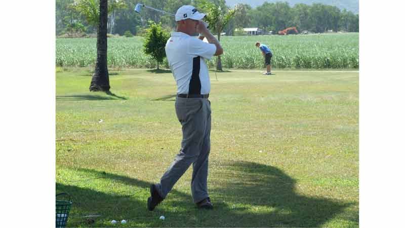 A man is swinging a golf club on a golf course.