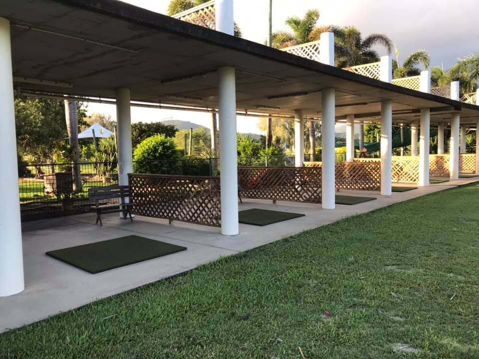 A row of golf mats are lined up under a covered area