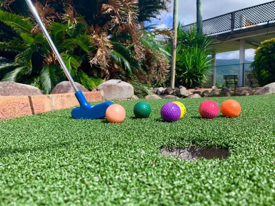 A person is playing mini golf on a lush green field.