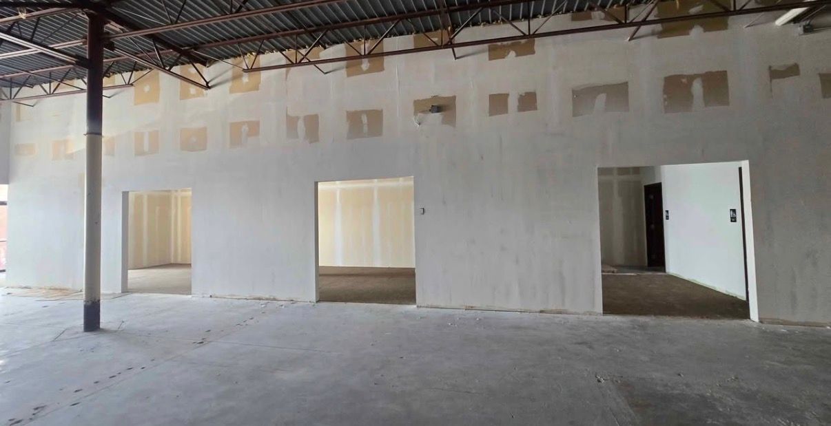 Interior view of unfinished commercial space with exposed ceiling, concrete floor, and doorways.