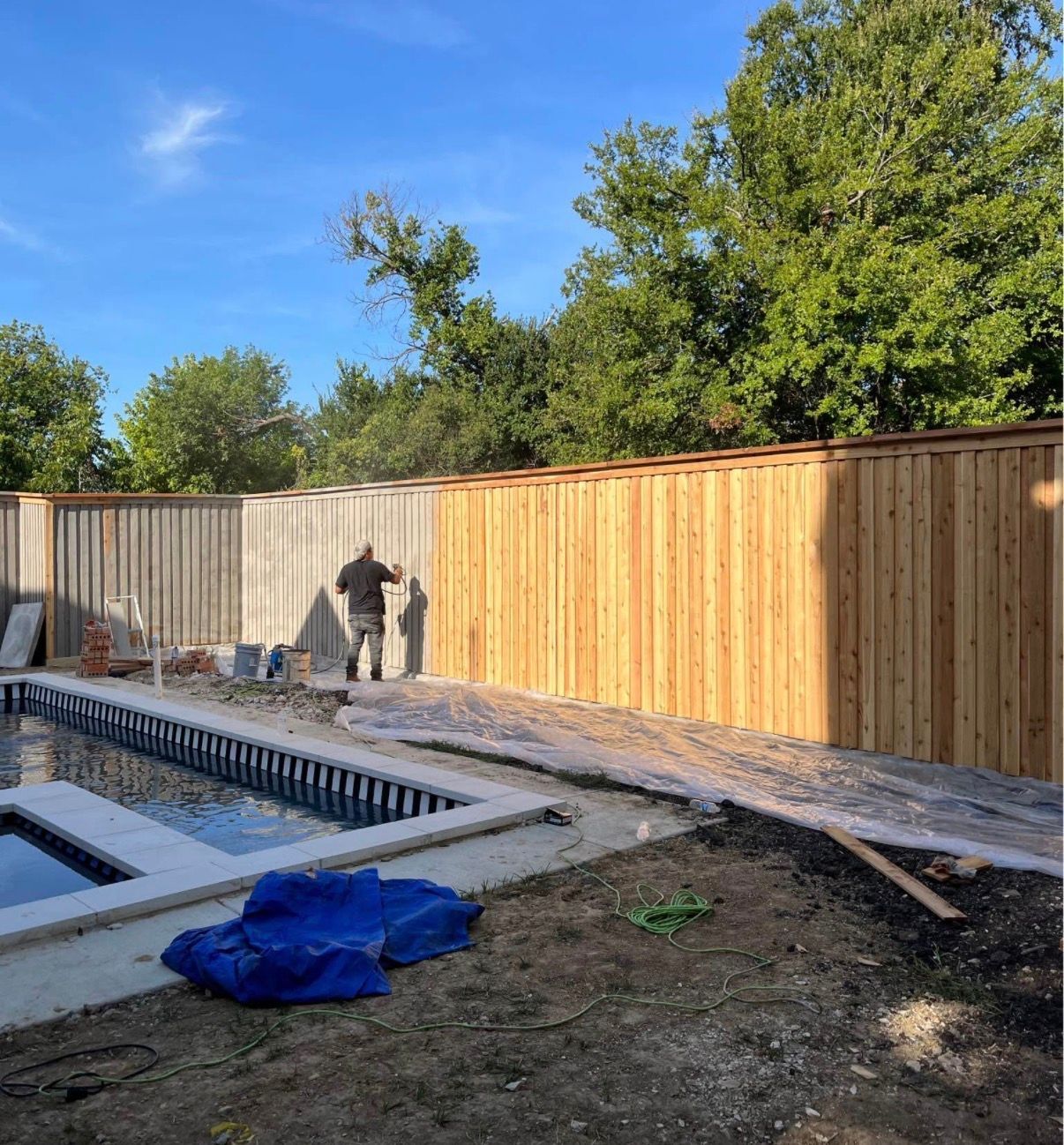Construction site: workers building a wooden fence next to a pool.