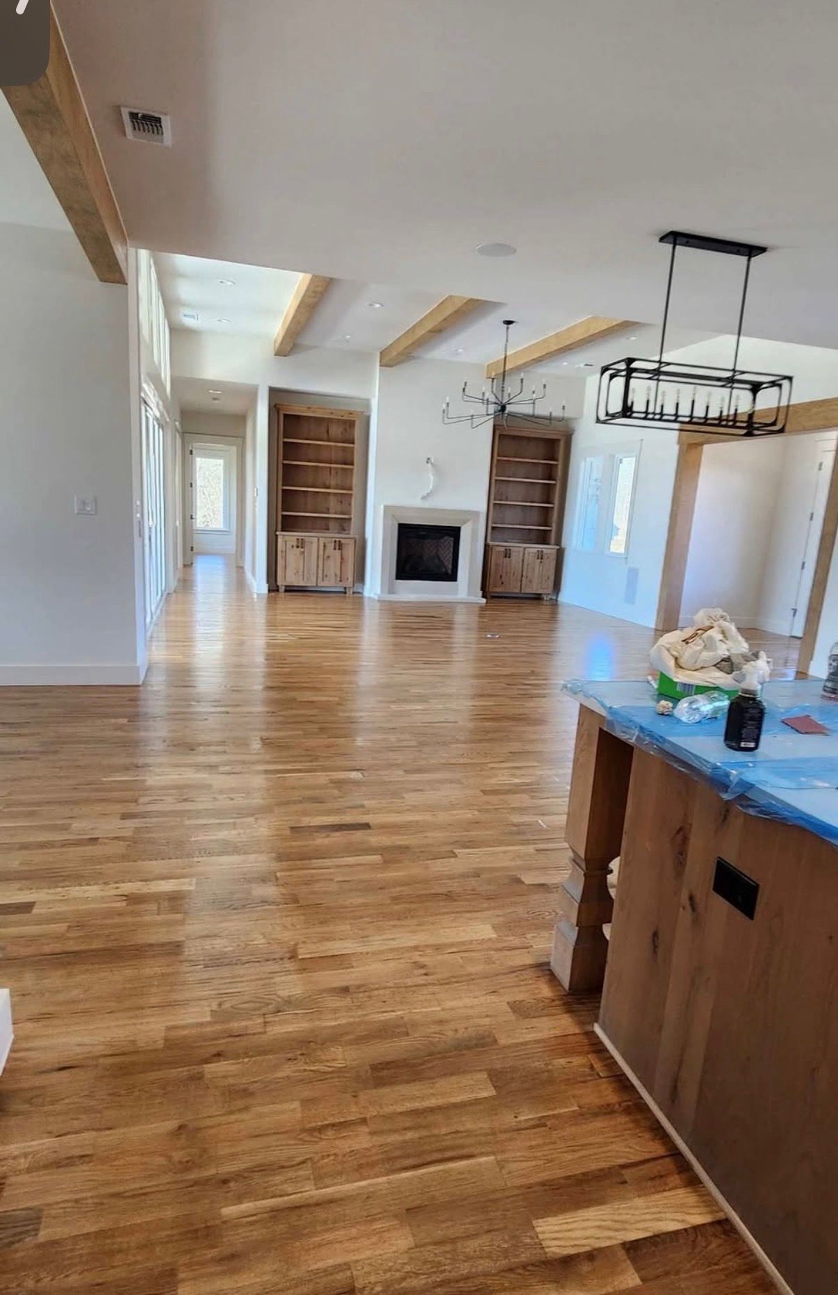Spacious living area with wooden floors, fireplace, built-in shelving, and island with blue countertop.