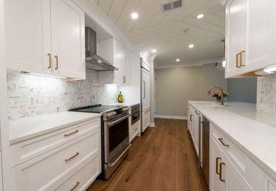White kitchen with island, cabinets, gray countertops, and black appliances.