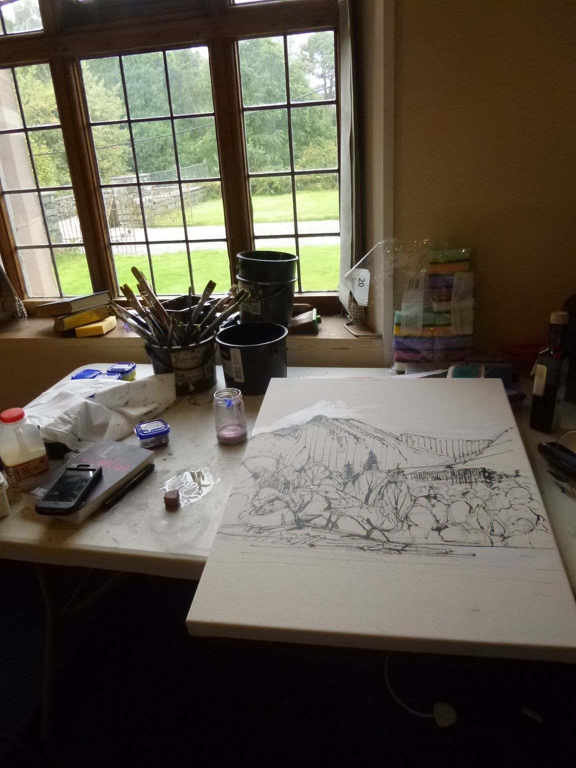 A painting is sitting on a table in front of a window.