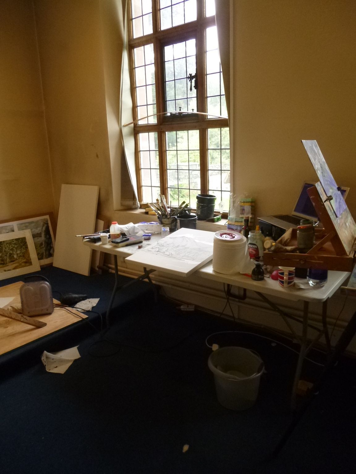 A messy room with a table and a window.