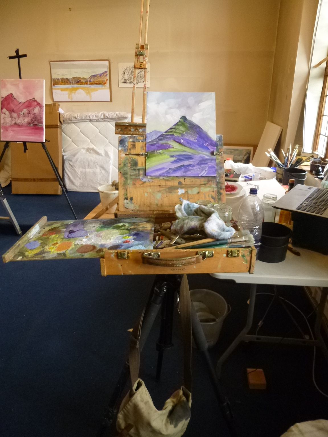 A painting is being painted on an easel in a studio.
