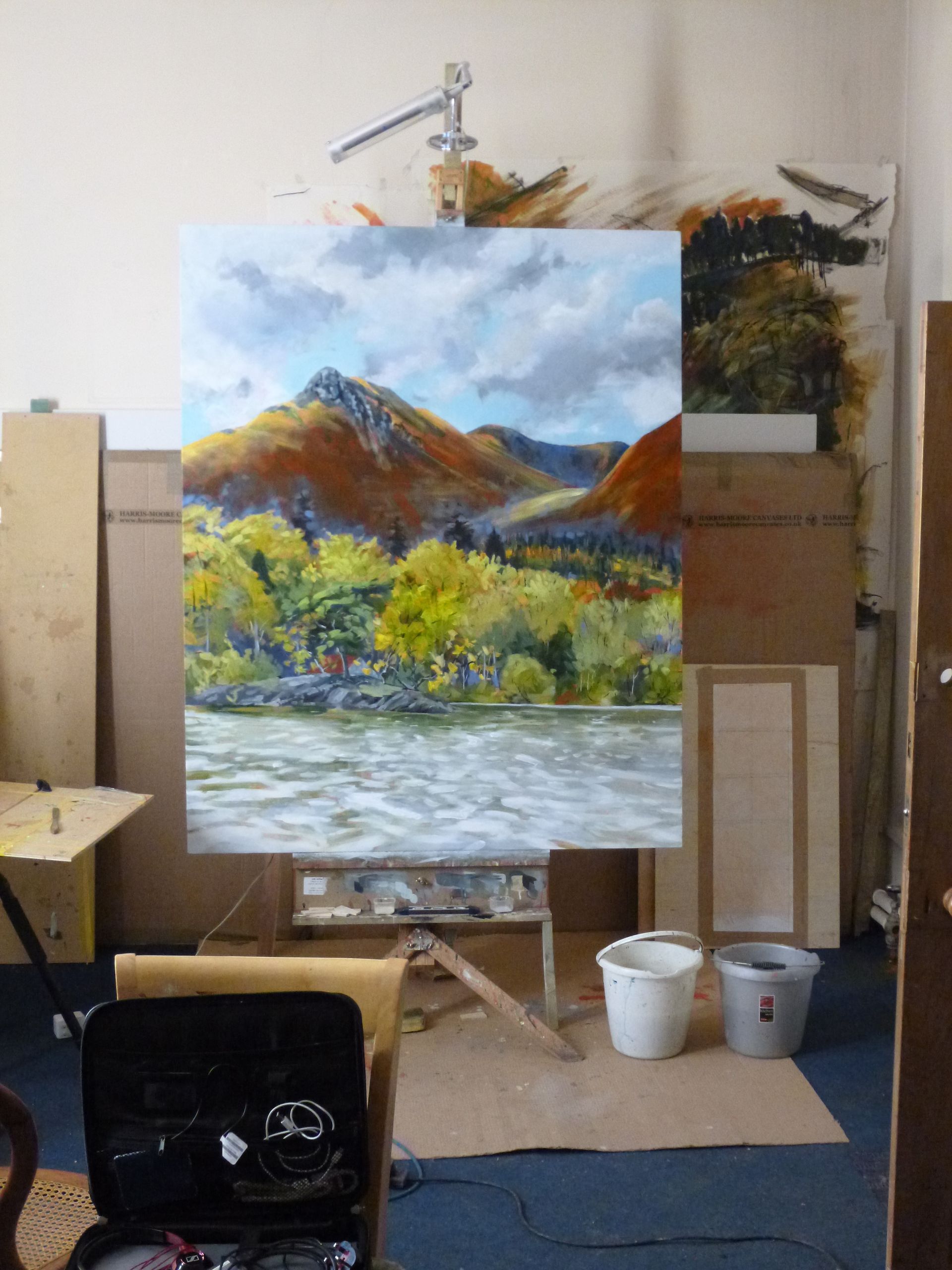 A large painting on an easel with mountains in the background