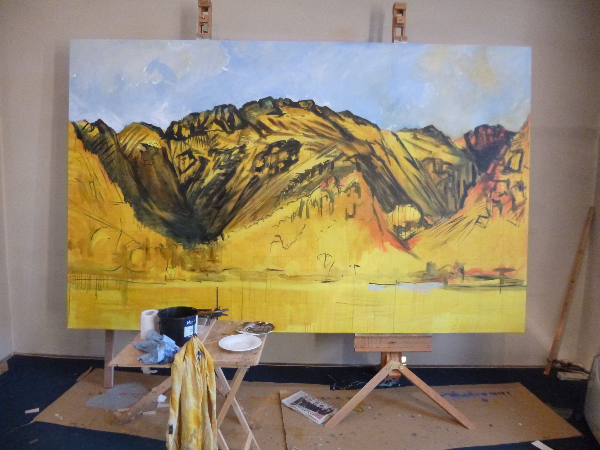 A large painting of a mountain is being painted on an easel