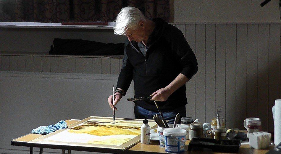 A man is painting a picture on a table with a brush.