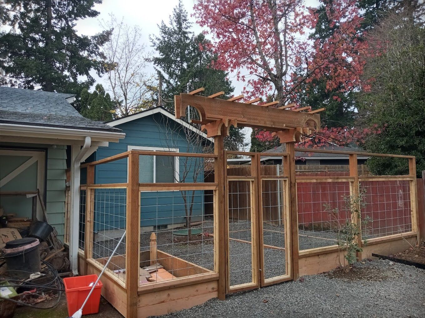 A wooden pergola is being built in front of a blue house.